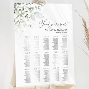May include: A white wedding seating chart with a leafy green floral design. The chart is titled "Find your seat" and includes the names Ashley & Richard and the date March 28, 2020. The chart lists tables 1 through 15 with guest names.