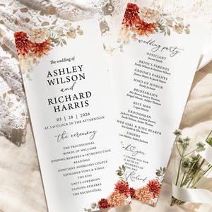 May include: Two wedding ceremony programs with floral accents. The programs are white with text in black, including the names Ashley Wilson and Richard Harris, and the date March 28, 2026. Floral arrangements in shades of red, orange, and cream adorn the corners.