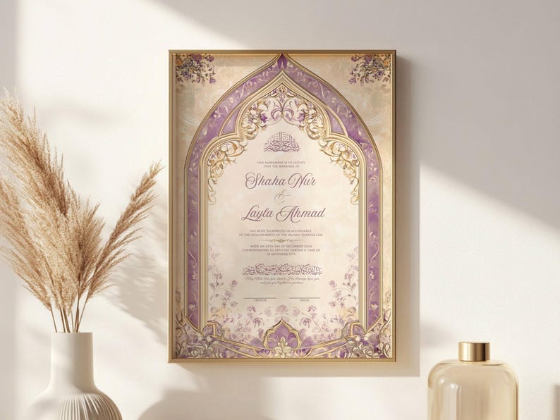 May include: A framed wedding invitation with a gold border. The invitation features a decorative arch design in shades of purple and gold, with floral accents. The names "Shaha Nur & Layla Ahmad" are displayed prominently.