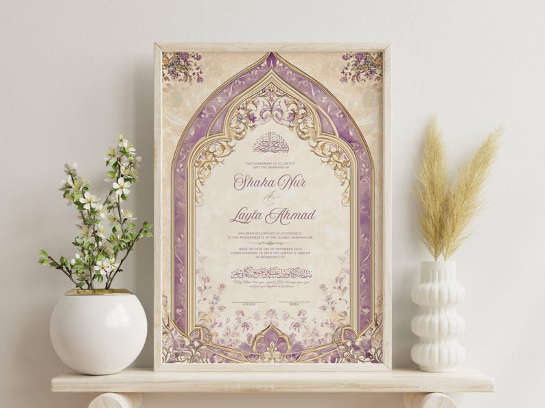 May include: Framed wedding certificate with a beige and purple floral design. The certificate features the names "Shaha Nur & Layla Ahmad" in elegant script. The frame is a light wood color, and the overall aesthetic is ornate and decorative.
