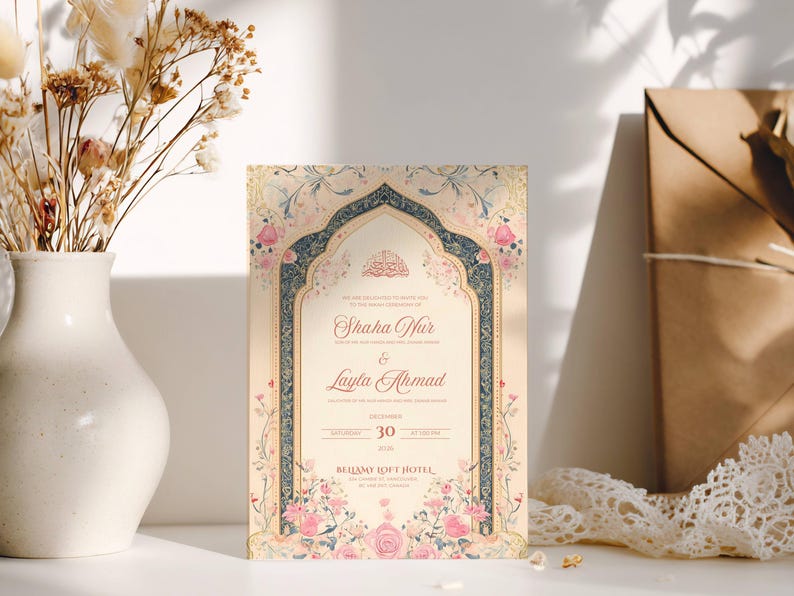 May include: An ornate wedding invitation with floral and archway designs. The invitation features the names "Shaha Nur" and "Layla Ahmad", along with the date December 30th. The invitation is surrounded by a white vase with dried flowers and a brown envelope.