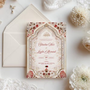 Puede incluir: Una invitaci&oacute;n de boda marfil con un dise&ntilde;o floral y ornamentado. La invitaci&oacute;n presenta los nombres "Shaha Nur & Layla Ahmad" en una fuente de escritura. La invitaci&oacute;n est&aacute; rodeada de flores blancas y un sobre marfil.