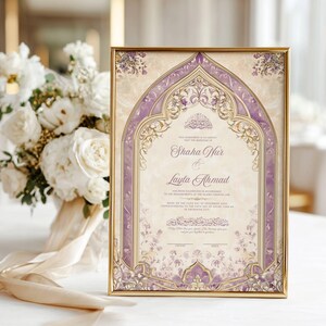 May include: A framed wedding invitation with ornate purple and gold detailing. The invitation features the names "Shaha Nur" and "Layla Ahmad" in elegant script. A bouquet of white flowers with a cream ribbon is in the background.