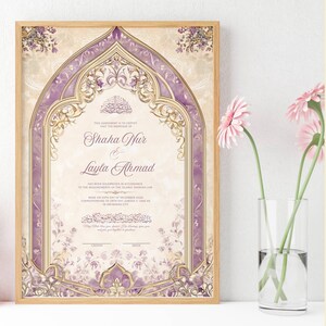 May include: Framed wedding certificate with a light wood frame. The certificate features a decorative arch design in shades of purple and gold, with floral accents. The names "Shaha Nur & Layla Ahmad" are displayed prominently. Pink flowers in a glass vase are in the foreground.