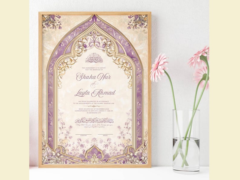 May include: Framed wedding certificate with a light wood frame. The certificate features a decorative arch design in shades of purple and gold, with floral accents. The names "Shaha Nur & Layla Ahmad" are displayed prominently. Pink flowers in a glass vase are in the foreground.