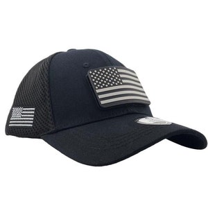 May include: Black baseball cap with a mesh back and a curved brim. The cap features a patch of the American flag on the front and a smaller flag patch on the side. The hat is a classic style.