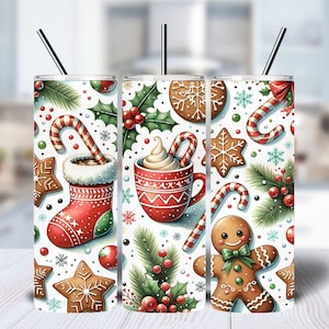 Könnte beinhalten: Drei Edelstahlbecher mit weißem Hintergrund und einem weihnachtlichen Design. Das Design zeigt Zuckerstangen, Lebkuchen, Stechpalmen und heiße Schokolade.