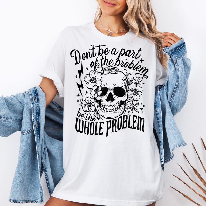 May include: White t-shirt with a black graphic of a skull surrounded by flowers. The text on the shirt reads "Don't be a part of the problem, be the WHOLE PROBLEM". The shirt is a casual, oversized fit.