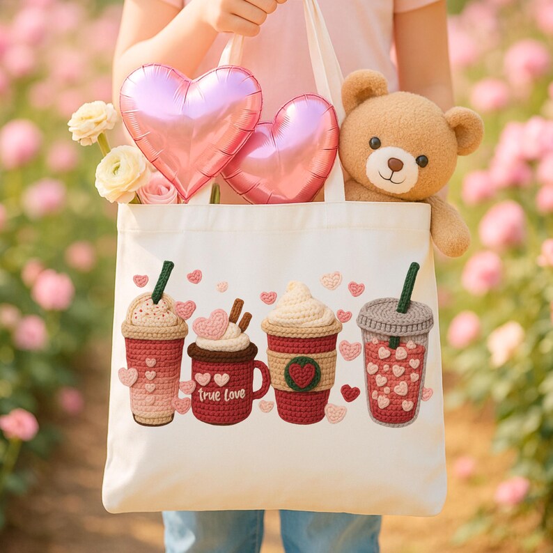 May include: A white tote bag with a crochet design of four coffee drinks and hearts. The bag also contains a teddy bear, pink heart-shaped balloons, and flowers. The words "true love" are on one of the coffee cups.
