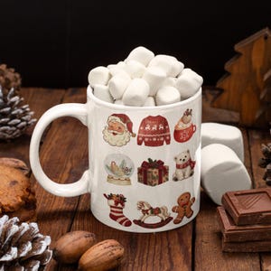 Könnte beinhalten: Ein weißer Keramikbecher gefüllt mit weißen Marshmallows, verziert mit einem wiederkehrenden Muster aus weihnachtlichen Illustrationen wie dem Weihnachtsmann, einem roten Pullover, einem Geschenk, einem Eisbären, einem Strumpf, einem Schaukelpferd und einem Lebkuchenmann.