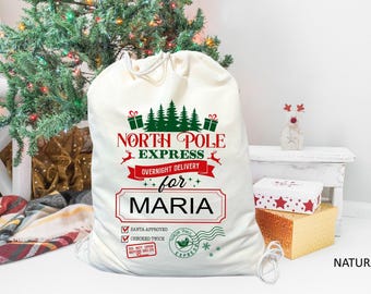 May include: White canvas Santa sack with red and green text that reads "North Pole Express Overnight Delivery for Maria". The sack has a red and green reindeer graphic and a green Christmas tree graphic.