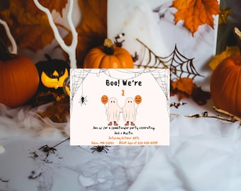 May include: A Halloween party invitation with a white background and a black spider web design. The invitation features two cartoon ghosts holding orange balloons with jack-o-lantern faces. The text reads "Boo! We're 2" and includes details about the party, including the date, time, and RSVP information.
