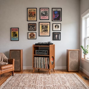 May include: A wooden media console with a turntable on top, an amplifier on the middle shelf, and a vinyl record collection on the bottom shelf. Eight framed music posters are displayed on the wall above the console and two speakers.