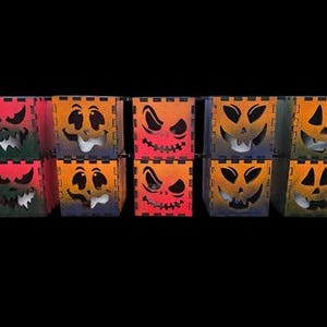 May include: A set of ten square wooden boxes arranged in two rows of five, each featuring a unique laser-cut jack-o'-lantern face. The boxes display gradient color schemes including orange, red, and purple, with black edges and visible joinery.