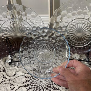 May include: A set of three clear glass plates with a bubbled texture. The plates are in various sizes and are stacked on top of each other.