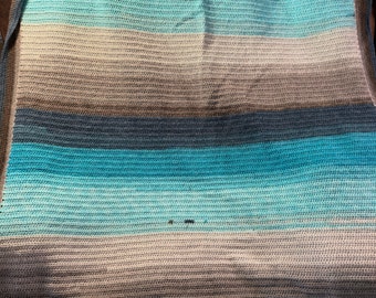 Könnte beinhalten: Gehäkelte Decke mit horizontalen Streifen in verschiedenen Blau-, Grau- und Weißtönen. Die Decke hat eine weiche Textur und einen Farbverlauf. Sie ist gefaltet und zeigt ihre volle Breite. Geeignet für Bett oder Sofa.