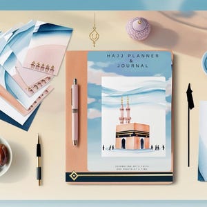 May include: A pink and blue planner and journal with the text "Hajj Planner & Journal" on the cover. The cover features a watercolour illustration of the Kaaba in Mecca, Saudi Arabia. The journal is open to a page with the text "Inspiration with every page, one drawing at a time."