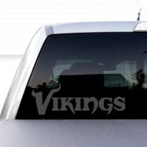 May include: A black truck with a black vinyl decal on the rear window that says "VIKINGS" in a stylized font.