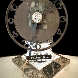May include: A unique, mixed-media clock sculpture featuring a vintage aesthetic. The clock face has a cutout metal frame with numbers, a photo of a man, and a clock mechanism. The base is decorated with clock faces and the words "Father Time".