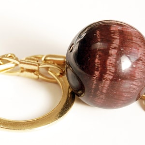 May include: A gold key chain with a large, round, red tiger's eye stone attached.