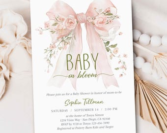 Puede incluir: Una invitación para un baby shower con un diseño de acuarela. La invitación presenta un gran lazo rosa adornado con flores y las palabras "BABY in bloom". Los detalles incluyen el nombre de la homenajeada, la fecha, la hora y el lugar.
