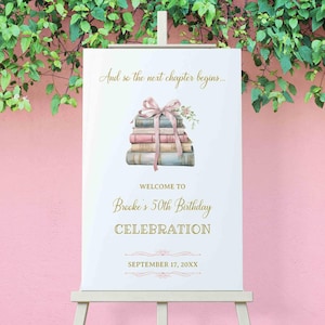 Pode incluir: Um cartaz de boas-vindas branco com texto dourado anunciando a celebração do 50º aniversário de Brooke em 17 de setembro de 20XX. O cartaz apresenta uma pilha de livros amarrados com uma fita rosa e um enfeite floral.