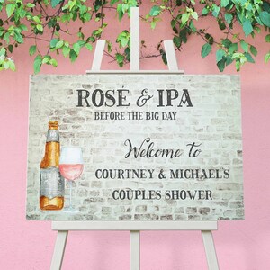 Op de afbeelding: Een witte bakstenen muur achtergrond met een bord waarop staat "Rose & IPA Before the Big Day" met een fles bier en een glas wijn. Het bord zegt ook "Welcome to Courtney & Michael's Couples Shower".