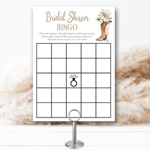 May include: A printable bridal shower bingo card with a floral and cowboy boot design. The card has a grid with 25 squares. The center square has a ring with a diamond. The text on the card reads "Bridal Shower Bingo" and "Fill in the squares with gifts that the bride may receive. If that gift is opened, Mark your square with an X. The first person to get 5 in a row wins!"