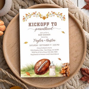 Könnte beinhalten: Eine weiße, rechteckige Einladungskarte für eine Babyparty mit einer Aquarellillustration von Herbstblättern oben sowie einem Football, einem Babyfläschchen und einer karierten Decke unten. Der Text lautet KICKOFF TO parenthood, Taylor + Austin.