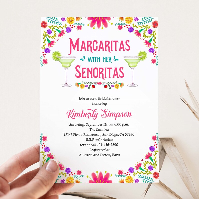 Op de afbeelding: Een witte bruidsdoucheinvitatie met een bloemige rand. De tekst luidt "Margaritas with her Senoritas" en bevat details voor een bruidsdouche ter ere van Kimberly Simpson. Het evenement is gepland op 11 september om 18:00 uur in The Cantina, gelegen aan Fiesta Boulevard 12345 in San Diego, CA 67890. De uitnodiging bevat ook de RSVP-informatie en de registratiegegevens.