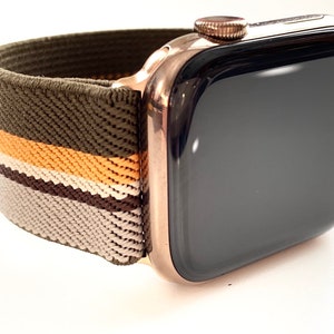 Könnte beinhalten: Eine Apple Watch in Roségold mit schwarzem Zifferblatt und einem grün-braun-weiß gestreiften Sportarmband.