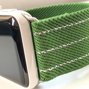 Puede incluir: Una correa de reloj verde con costuras plateadas. La correa est&aacute; hecha de un tejido tejido y tiene una superficie texturizada.