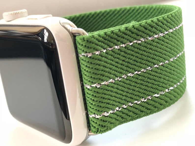 Puede incluir: Una correa de reloj verde con costuras plateadas. La correa est&aacute; hecha de un tejido tejido y tiene una superficie texturizada.