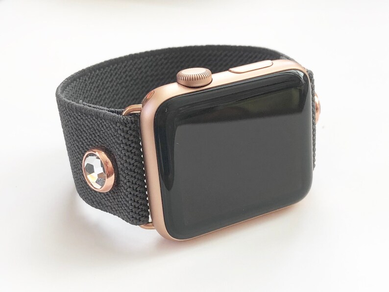 May include: A rose gold Apple Watch with a black sport band and clear crystal accents.