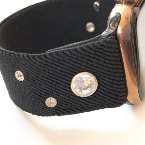 May include: A black watch band with rhinestones. The band is made of a stretchy material and has a rose gold watch face.
