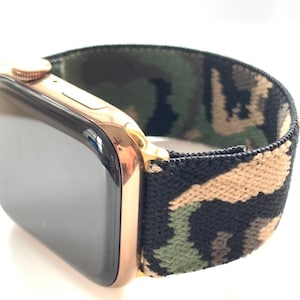 Puede incluir: Un Apple Watch dorado con una banda elástica de camuflaje negro y verde.