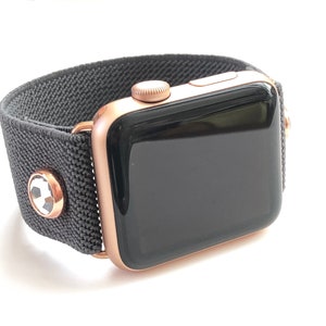 May include: A rose gold Apple Watch with a black sport band. The band has a soccer ball design on the buckle.