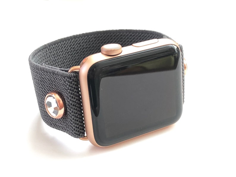 May include: A rose gold Apple Watch with a black sport band. The band has a soccer ball design on the buckle.