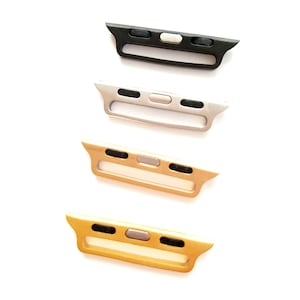 May include: Four Apple Watch band adapters in different colors: black, silver, gold, and rose gold. Each adapter has a small button on the top.