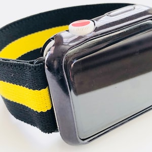 May include: Black Apple Watch with a black and yellow striped elastic band. The watch has a black screen and a silver button on the side.