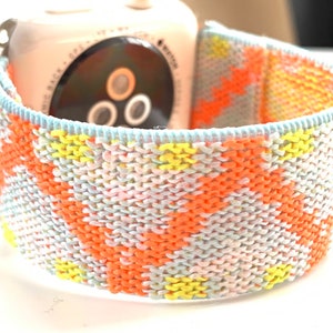 May include: A colorful woven Apple Watch band with a light blue, pink, yellow, and orange geometric pattern.