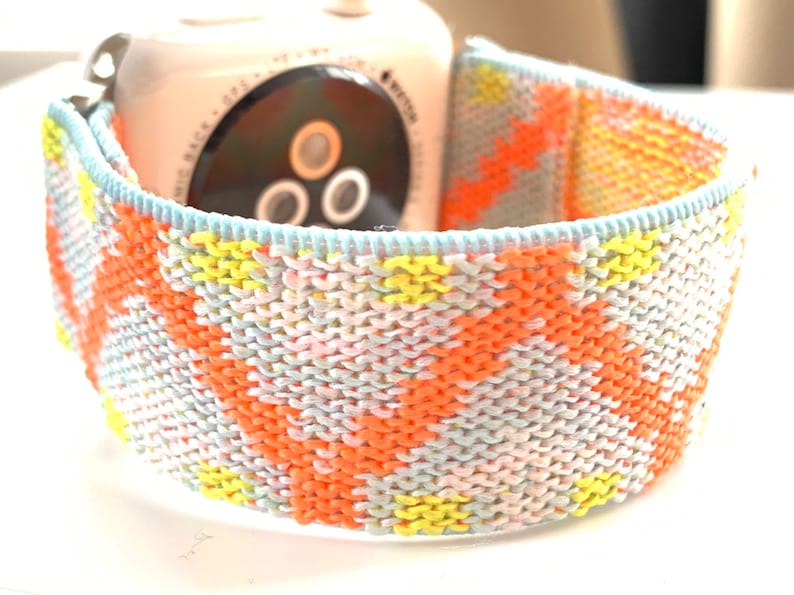 May include: A colorful woven Apple Watch band with a light blue, pink, yellow, and orange geometric pattern.