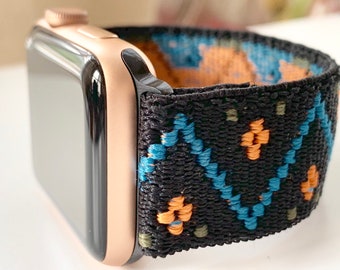 May include: A rose gold Apple Watch with a black and blue patterned sport band. The band has a geometric design with orange, blue, and green accents.
