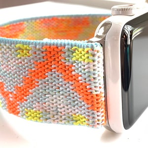 May include: A colorful knitted Apple Watch band with a white and black Apple Watch.