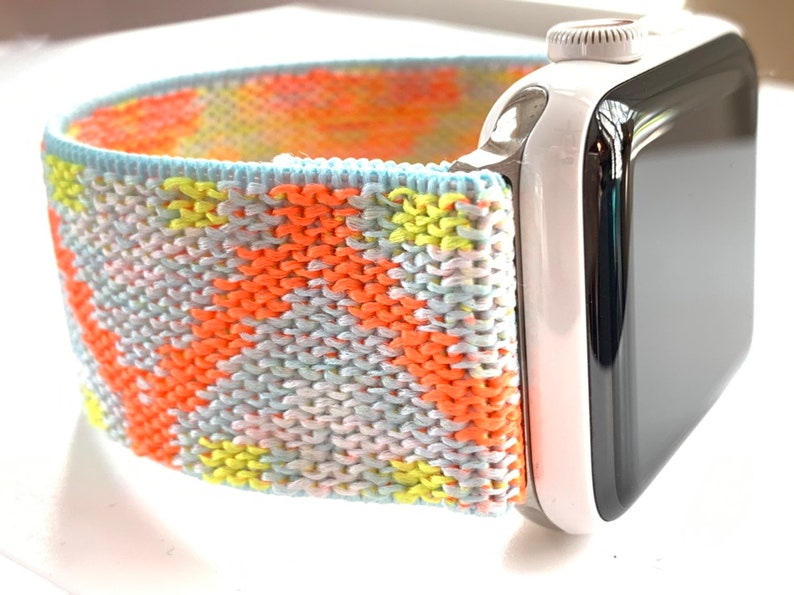 May include: A colorful knitted Apple Watch band with a white and black Apple Watch.