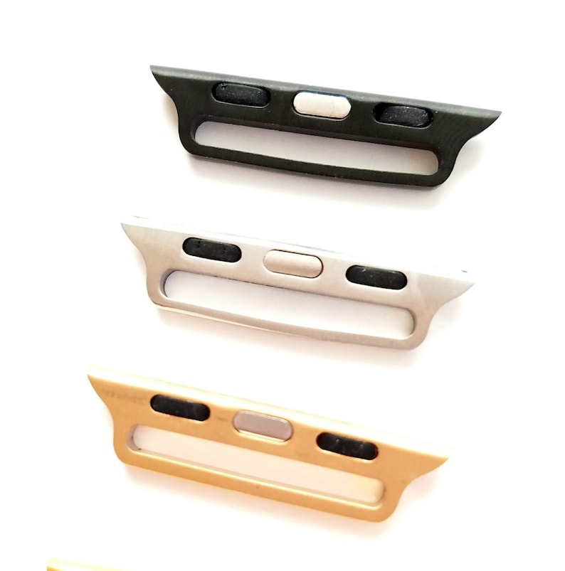 May include: Three Apple Watch band adapters in black, silver, and gold. Each adapter has a slot for a watch band and three buttons.