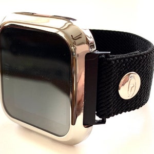 May include: A silver-colored smartwatch with a black elastic band. The band has a silver buckle and a silver logo on the side.