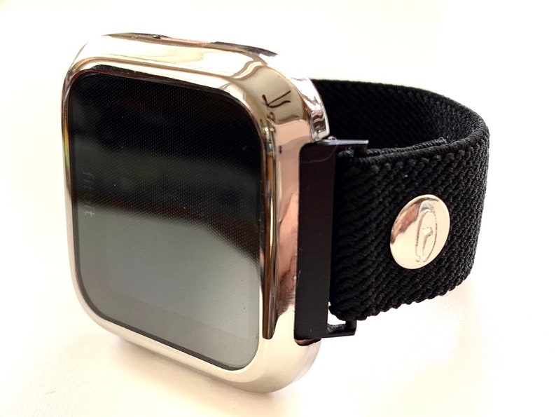 May include: A silver-colored smartwatch with a black elastic band. The band has a silver buckle and a silver logo on the side.