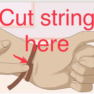 May include: A brown leather strap with the text "Cut string here" written in red.