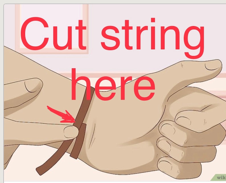 May include: A brown leather strap with the text "Cut string here" written in red.